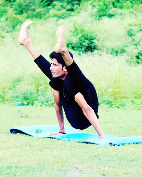 An Utkrisht Yoga coach holding a standing balance on a mat outdoors