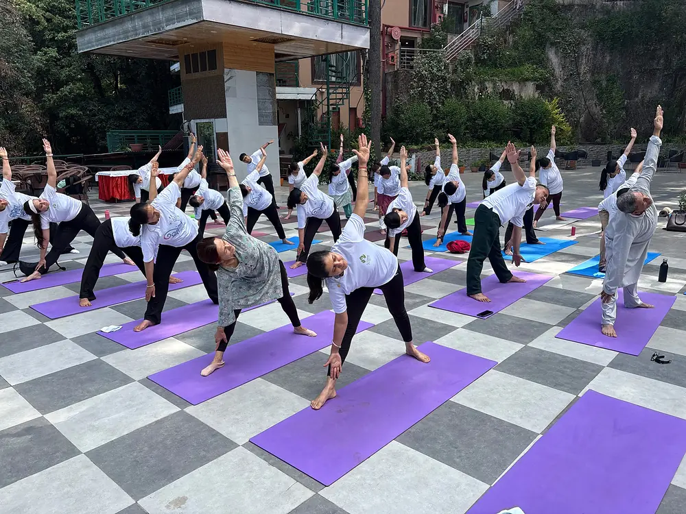 A whole class holding triangle pose together on mats in the open air