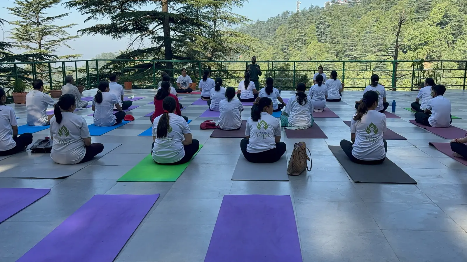 An Utkrisht Yoga community class seated in meditation on a terrace above the Shimla forest