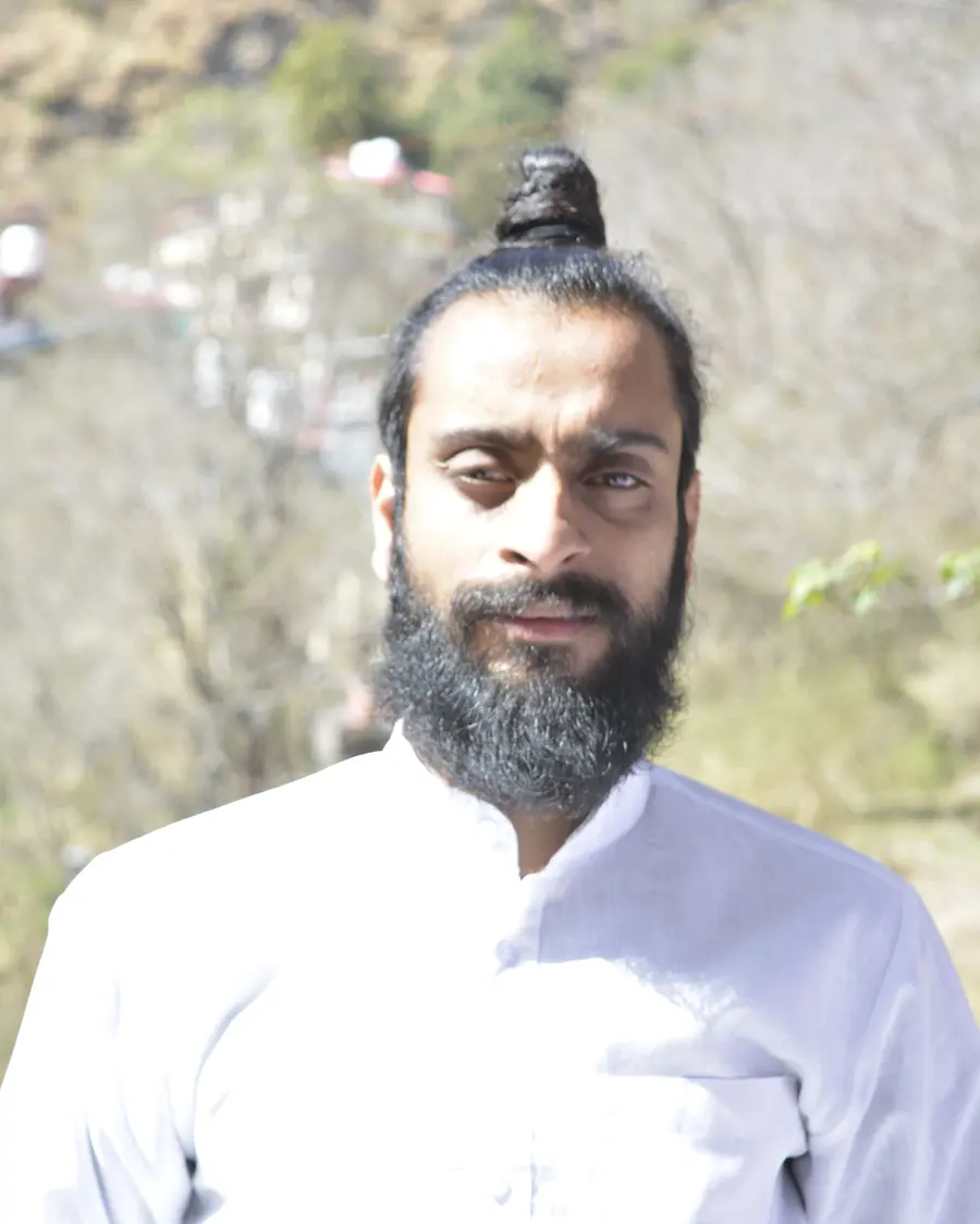 Umesh Yogi, founder of Utkrisht Yoga, in a white kurta on a Himachal hillside